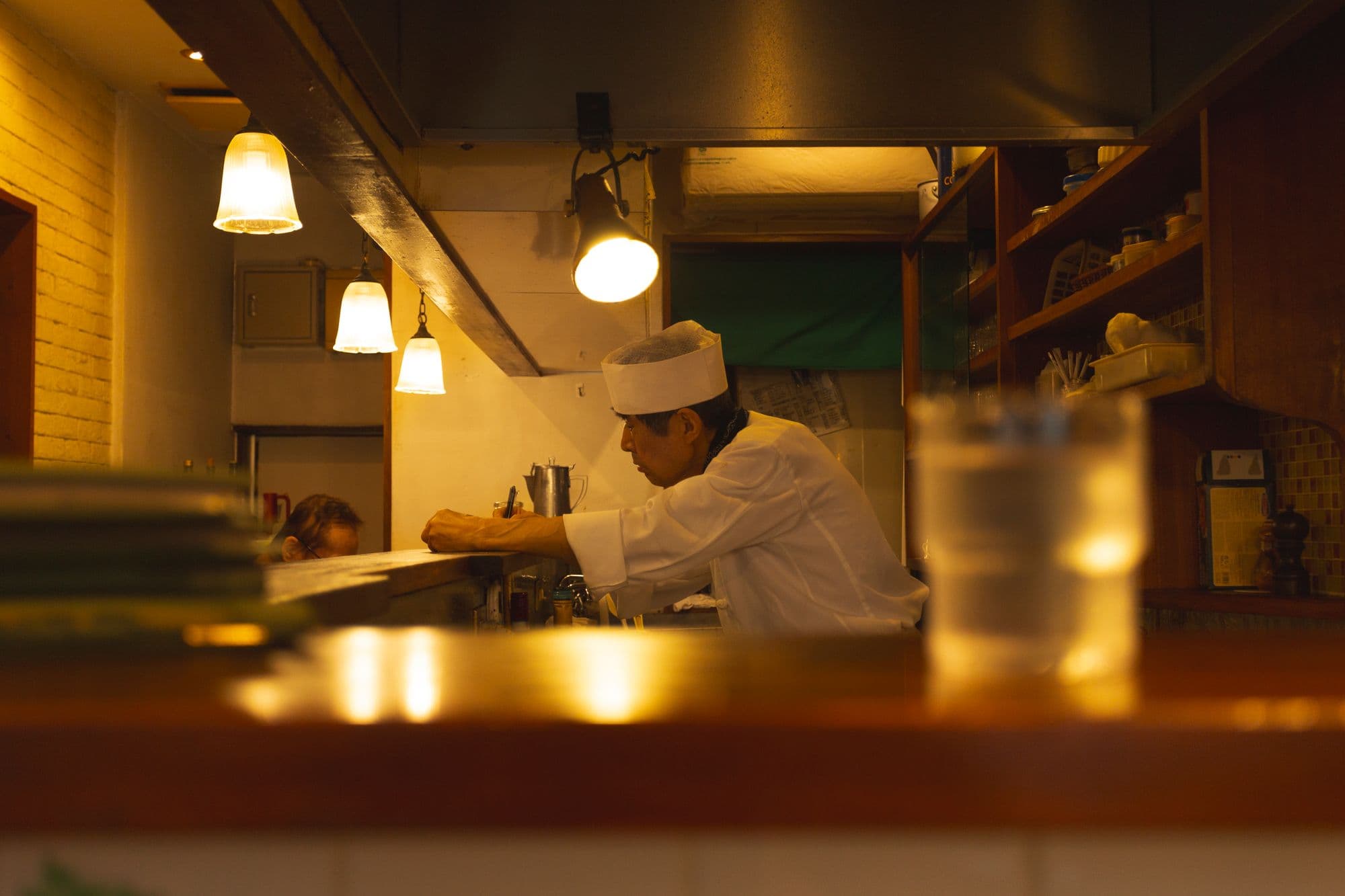 あたたかい照明の厨房で、料理人が調理をしている様子