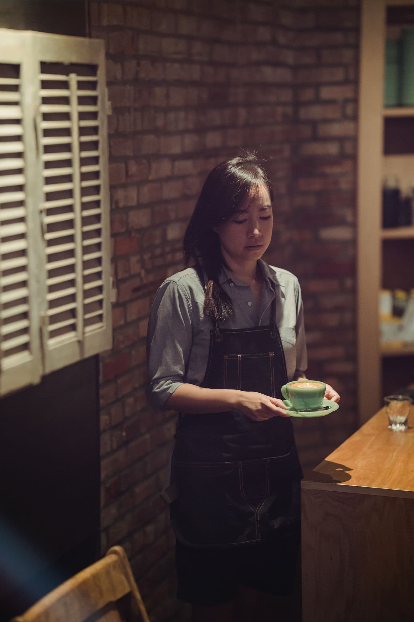 エプロン姿で、カップを運ぶカフェのスタッフ
